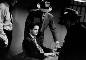Three detectives interrogating a suspect in a dimly lit room.